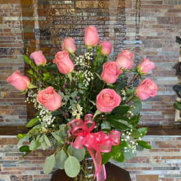 Pink roses in a clear glass vase with a pink ribbon