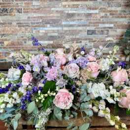 Large pastel floral arrangement with pink and white roses and purple flowers