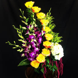 Tall arrangement of yellow roses, purple orchids, and white hydrangea in a vase