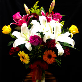 Mixed bouquet with white lilies, pink roses, and gerbera daisies in a glass vase