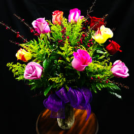 Bouquet of multicolored roses in a glass vase with a purple ribbon