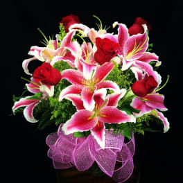 Bouquet of pink lilies and red roses with a purple ribbon wrap
