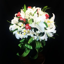 Bouquet of white lilies and red roses with a green ribbon bow
