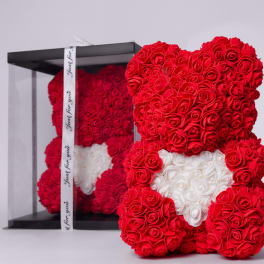 Red rose teddy bear with a white heart in a clear gift box