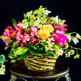 Basket arrangement of pink flowers and yellow roses with trailing ivy