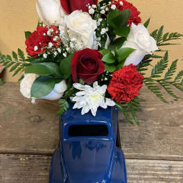 Red and white roses with red carnations in a blue truck vase