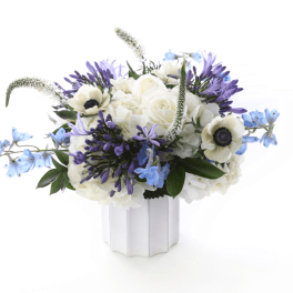 White and purple floral arrangement in a white vase with blue accents