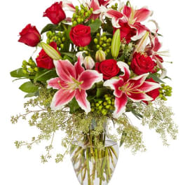 Red roses and pink lilies arranged in a clear glass vase