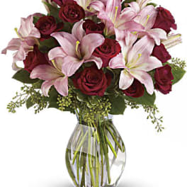 Bouquet of pink lilies and red roses in a clear glass vase