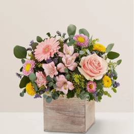 Pink and yellow mixed flower arrangement in a wooden box