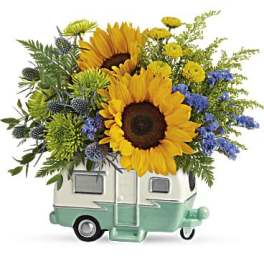 Sunflowers and mixed blooms arranged in a small camper-shaped container