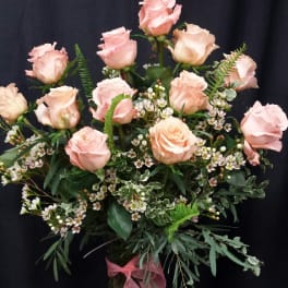 Pink roses arranged in a glass vase with a pink ribbon