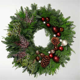 Christmas wreath with evergreen branches, red ornaments, and pinecones