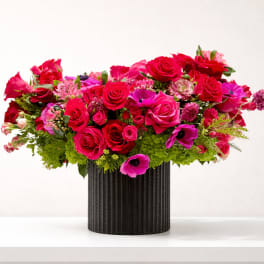 Bright pink and red flower arrangement in a black vase