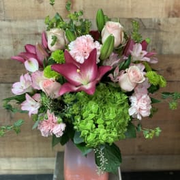 Pink lilies, roses, carnations, and green hydrangea in a vase
