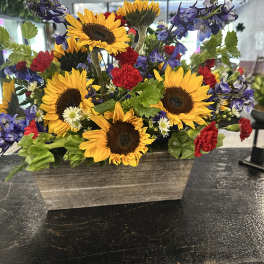 Sunflower arrangement with purple and red flowers in a rectangular wooden planter