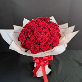 Bouquet of red roses wrapped in white paper with a red ribbon