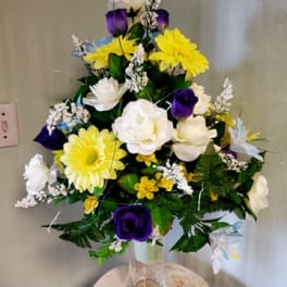 Mixed bouquet of yellow, white, and purple flowers in a clear glass vase