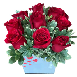 Red roses arranged in a blue heart-decorated container