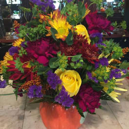 Colorful mixed flower arrangement in an orange vase