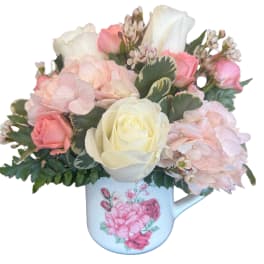 Pink and white roses with hydrangeas in a floral mug
