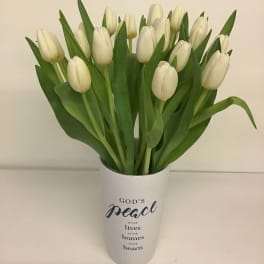 White tulips in a white vase with a peace message