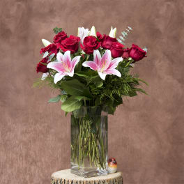 Bouquet of red roses and pink lilies in a clear glass vase