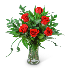 Red roses arranged in a clear glass vase with greenery