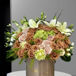 Large bouquet of tan and blush roses with white lilies in a gold box