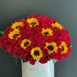 Red roses and yellow sunflowers in a white hat box