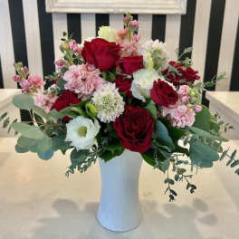 Red and white roses with pink flowers in a white vase
