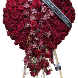 Heart-shaped red rose standing spray with a memorial ribbon