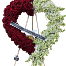 Heart-shaped floral tribute of red roses and white flowers on an easel