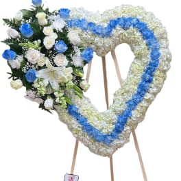 Heart-shaped floral wreath on an easel with blue and white flowers