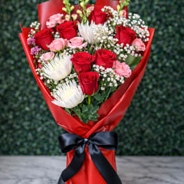 Bouquet of red and pink roses with white blooms wrapped in red paper