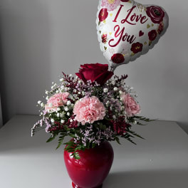 Pink carnation arrangement in a red vase with a heart balloon