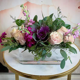 Pink and purple floral arrangement in a clear rectangular vase