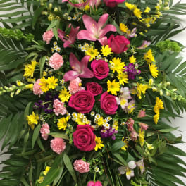 Large standing floral spray with pink roses, lilies, and yellow daisies