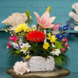 Mixed bouquet in a white basket with a pink lily and bright gerbera daisy