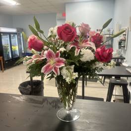 Pink roses and lilies arranged in a clear glass vase