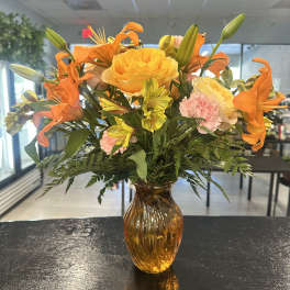 Orange lilies and yellow roses in an amber glass vase