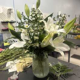 White lilies and small white daisies in a glass vase