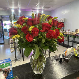 Bouquet of red roses and yellow filler flowers in a clear glass vase