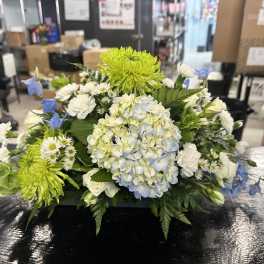 Low floral arrangement with blue hydrangea, green chrysanthemums, and white blooms