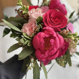 Handheld bouquet of hot pink peonies and pale pink roses