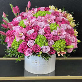 Large pink and lavender flower arrangement in a white box