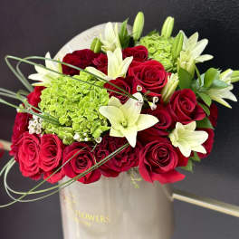 Red roses and white lilies in a beige hatbox
