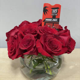 Red roses arranged in a round glass vase with a Trader Joe's tag
