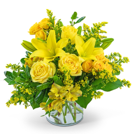 Yellow roses and lilies arranged in a clear glass vase