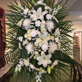 Large white funeral spray with lilies and chrysanthemums on a stand